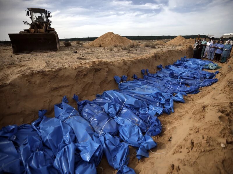 Palestinians pray over bodies of people killed in an Israeli bombardment, brought from the Shifa hospital, before burying them in a mass grave in the town of Khan Younis, southern Gaza Strip, Nov. 22.Mohammed Dahman/AP
