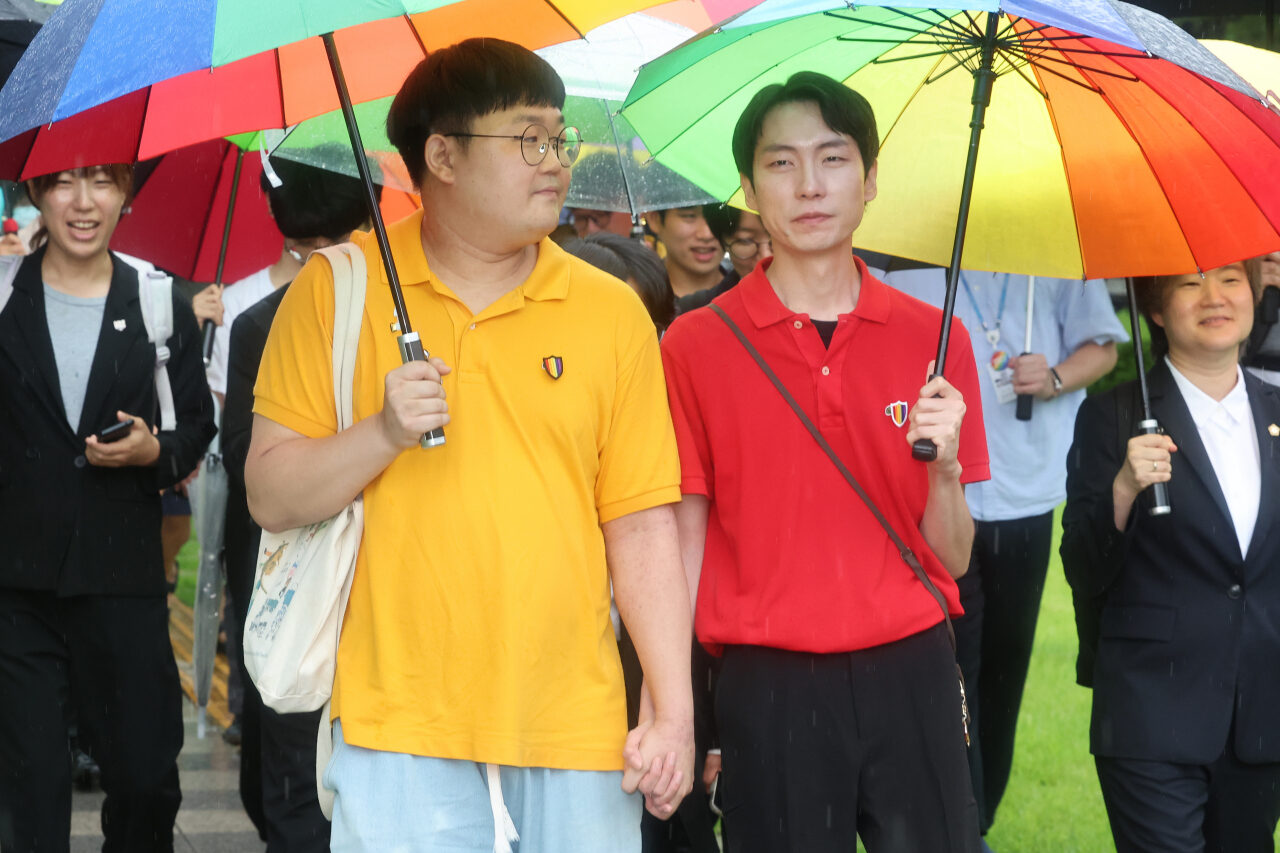 Same-sex partners So Sung-wook, left, and Kim Yong-min hold hands as they leave the Supreme Court in Seocho-gu, southern Seoul, Thursday. (Yonhap)
